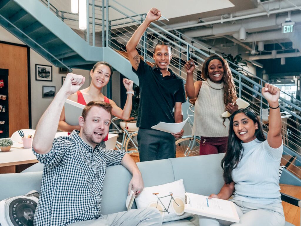 pexels-photo-7688168 A diverse group of coworkers cheerfully celebrating success in a modern office setting.